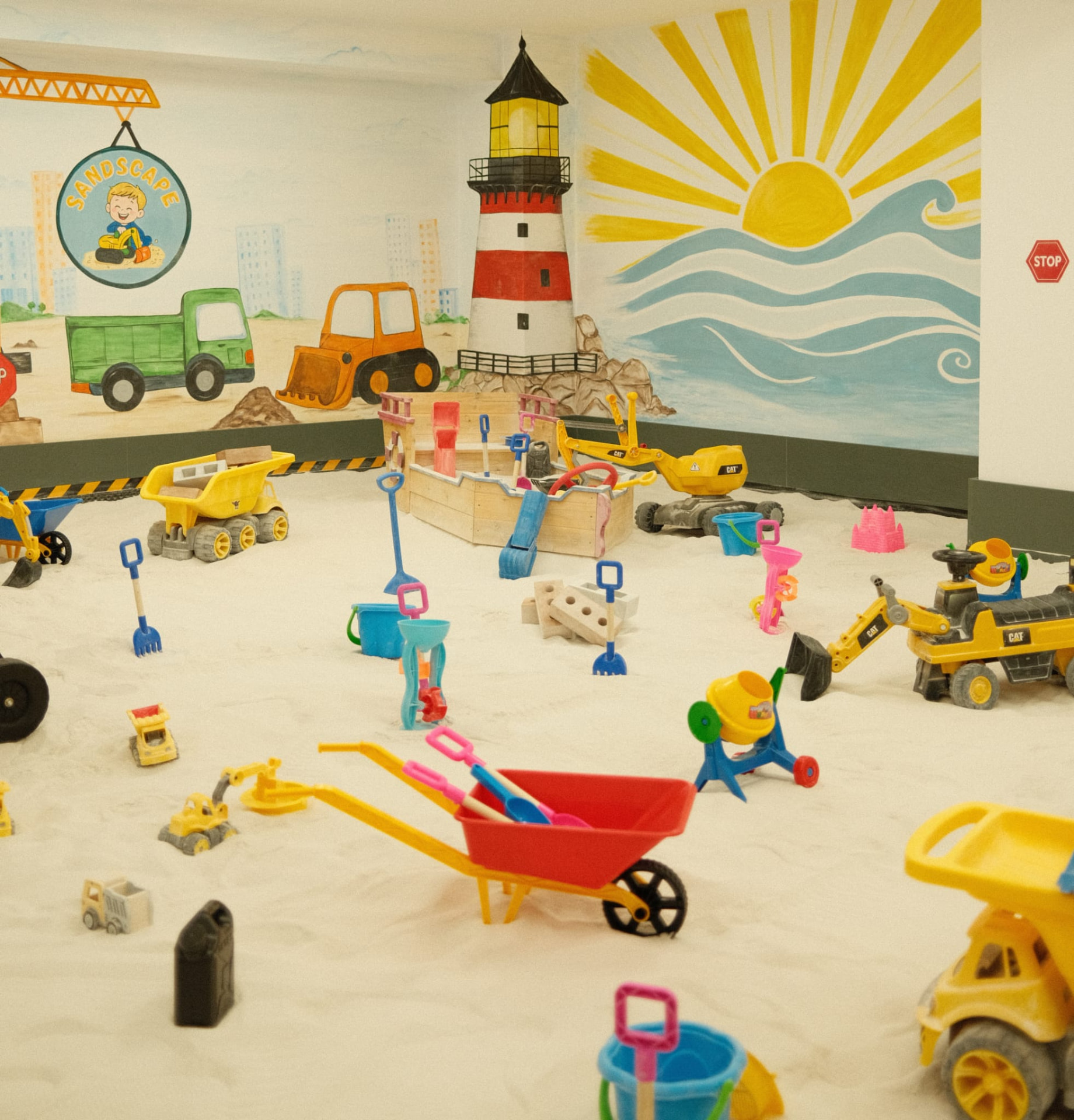 Zonă de joacă interior cu nisip, plină de excavatoare, camioane și jucării la SandScape Iași